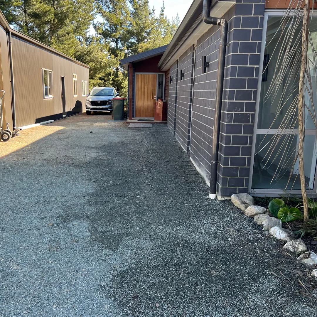 Tidy gravel driveway alongside a dark brick home